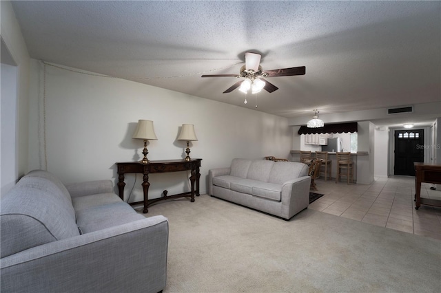 living room featuring a textured ceiling, ceiling fan, and light tile floors