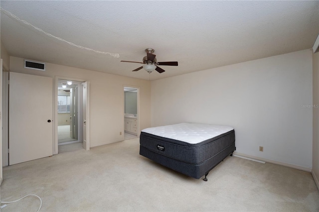 carpeted bedroom with a textured ceiling, ceiling fan, and connected bathroom