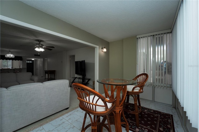 dining area featuring ceiling fan, light tile flooring, and a textured ceiling