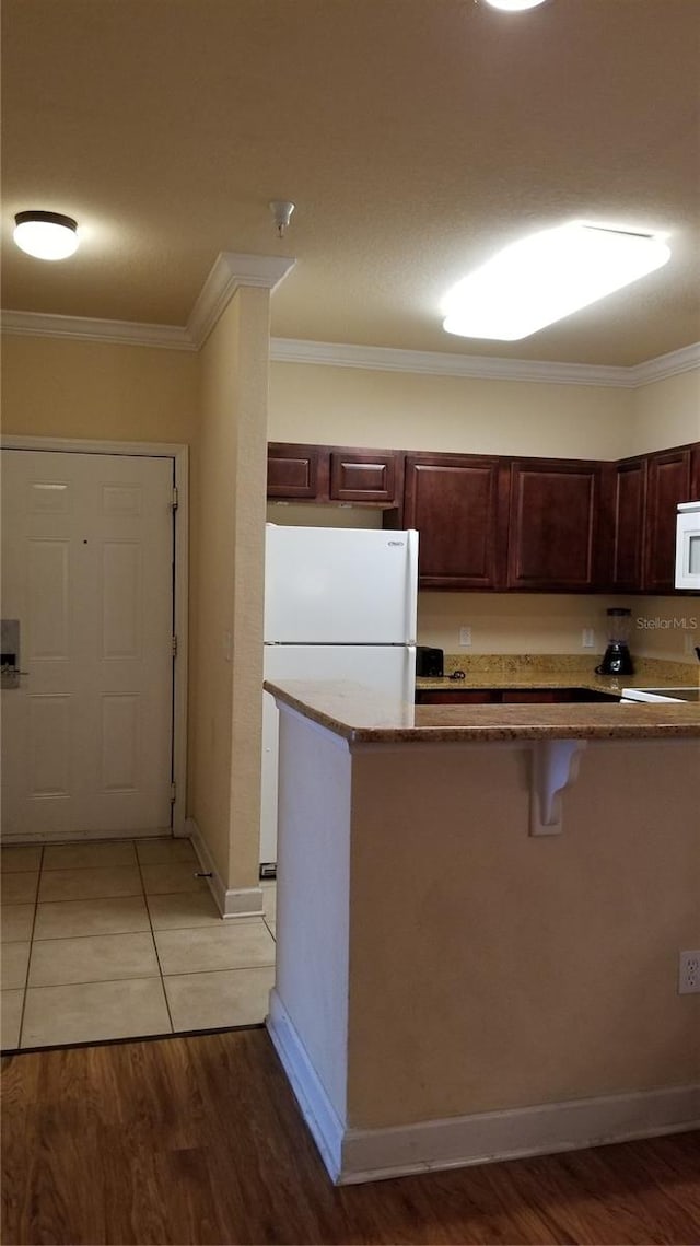 kitchen with white appliances, light wood-type flooring, and ornamental molding