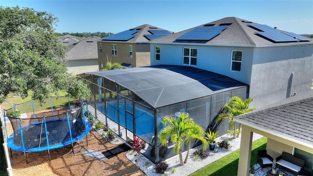 view of front of house with a fenced in pool, glass enclosure, a patio area, and a trampoline