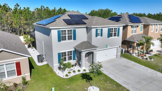 view of front property with a front yard, solar panels, a garage, and central AC unit