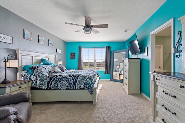 bedroom with a textured ceiling, light colored carpet, and ceiling fan