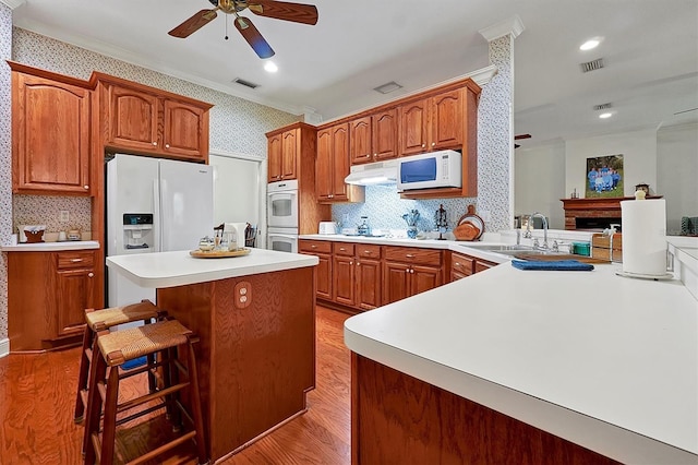 kitchen with light hardwood / wood-style flooring, kitchen peninsula, ceiling fan, tasteful backsplash, and white appliances