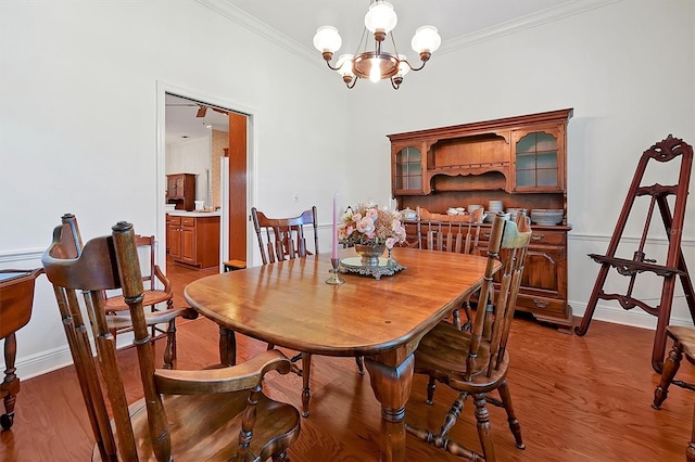 dining area featuring wood-type flooring, an inviting chandelier, and crown molding