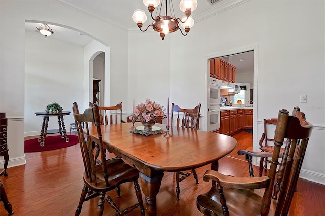 dining area with an inviting chandelier, crown molding, and hardwood / wood-style flooring