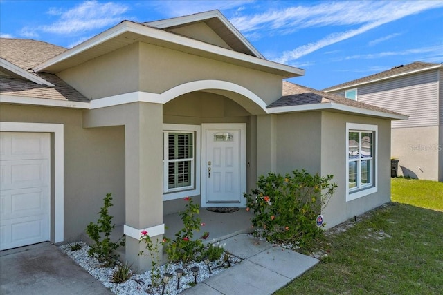 view of exterior entry featuring a yard and a garage