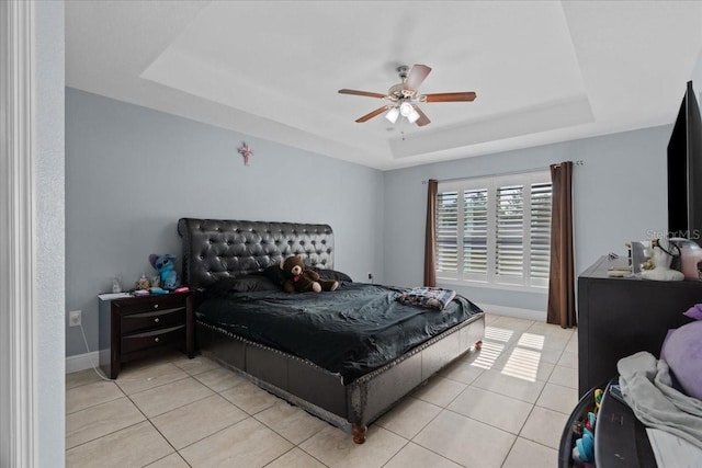 tiled bedroom featuring ceiling fan and a tray ceiling