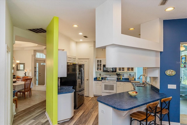 kitchen with a breakfast bar, black appliances, sink, dark hardwood / wood-style flooring, and kitchen peninsula