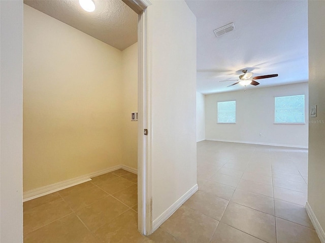 hall with a textured ceiling and tile flooring