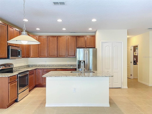 kitchen with appliances with stainless steel finishes, a center island with sink, light tile floors, and hanging light fixtures