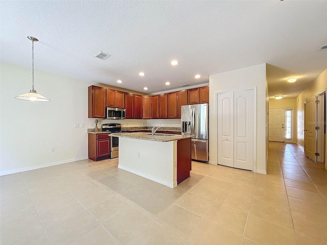 kitchen with appliances with stainless steel finishes, sink, light tile flooring, hanging light fixtures, and a kitchen island with sink