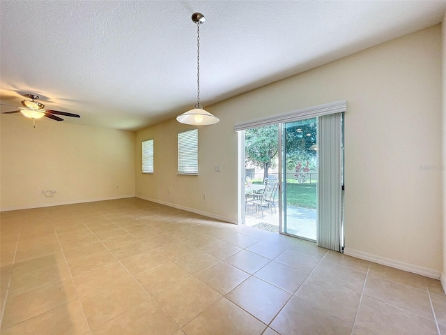 tiled empty room featuring ceiling fan and a textured ceiling