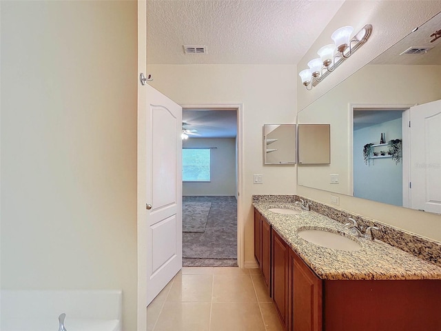 bathroom with double sink, oversized vanity, tile flooring, ceiling fan, and a textured ceiling