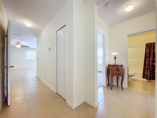 hall featuring a textured ceiling and light tile flooring