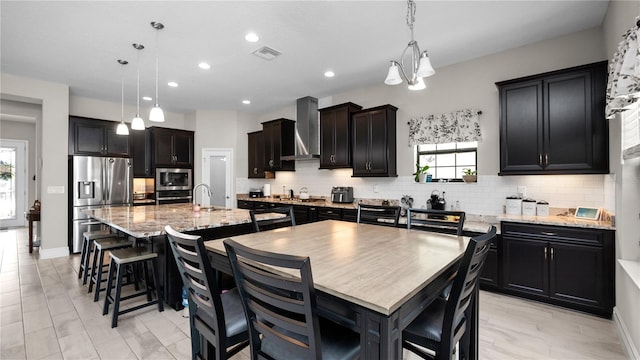 kitchen with a center island with sink, plenty of natural light, stainless steel appliances, and decorative light fixtures