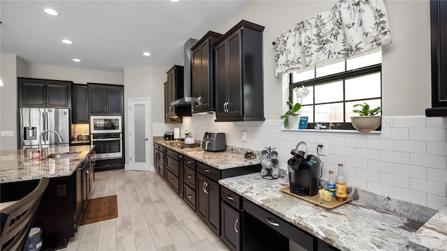 kitchen featuring backsplash, sink, light stone countertops, light hardwood / wood-style floors, and stainless steel appliances