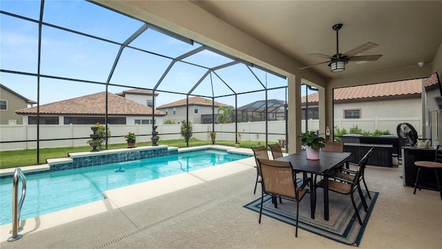 view of pool with pool water feature, a patio, glass enclosure, and ceiling fan