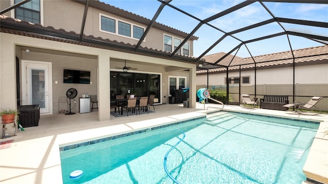 view of pool featuring glass enclosure, ceiling fan, and a patio area