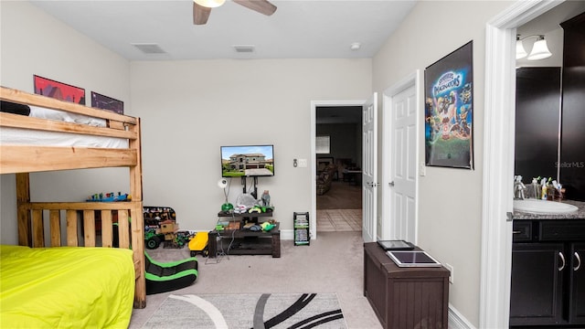 bedroom with ceiling fan, sink, connected bathroom, and light carpet