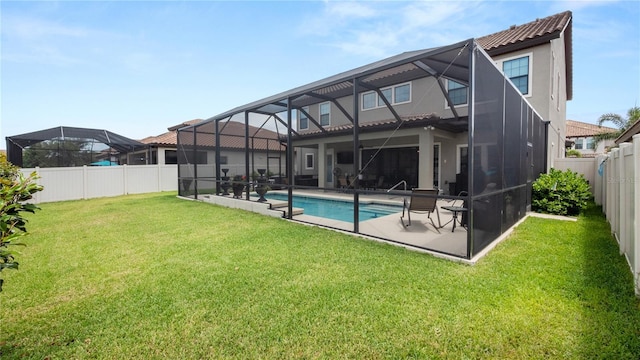 back of property with a fenced in pool, glass enclosure, a patio area, and a lawn