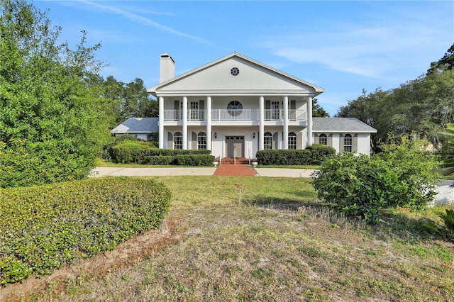 greek revival house with a balcony and a front yard