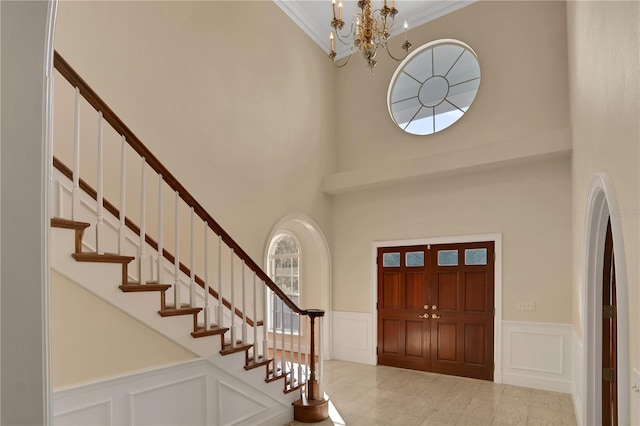 foyer entrance with a high ceiling, an inviting chandelier, and ornamental molding