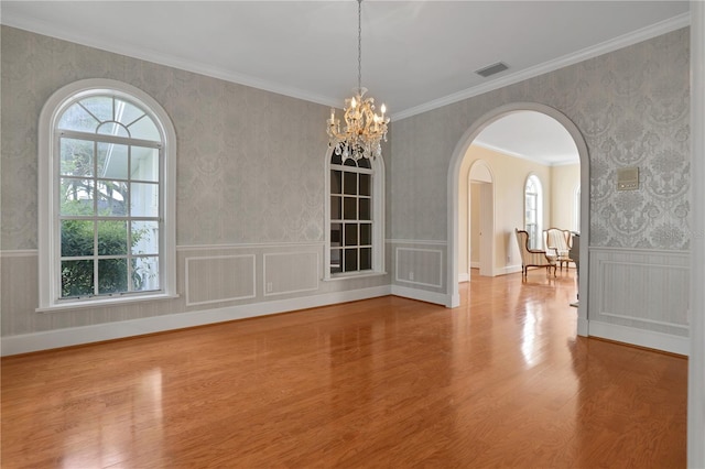 unfurnished dining area with wood-type flooring, a chandelier, and crown molding