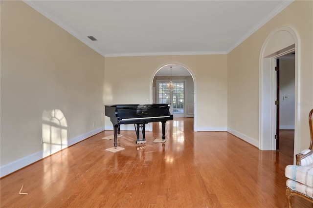 miscellaneous room featuring an inviting chandelier, ornamental molding, and hardwood / wood-style flooring