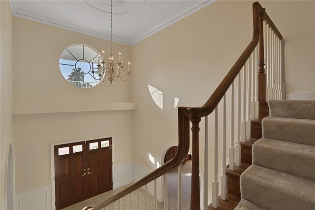 foyer entrance with a notable chandelier, hardwood / wood-style floors, and crown molding