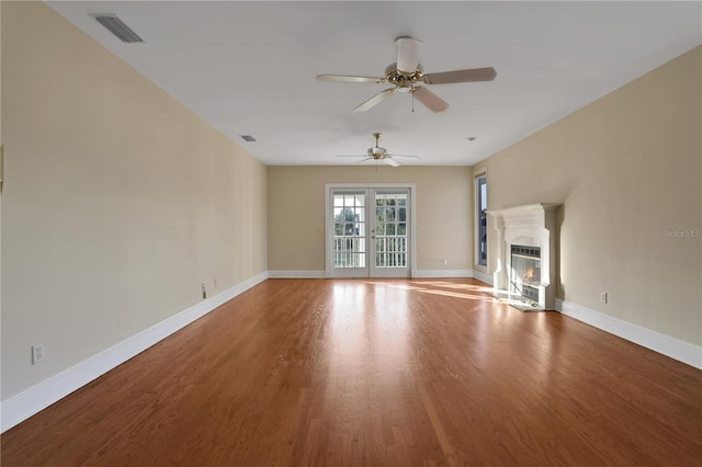 unfurnished living room featuring ceiling fan, heating unit, and hardwood / wood-style flooring