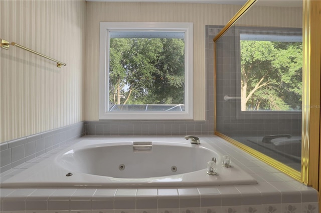 bathroom featuring a relaxing tiled tub and a wealth of natural light