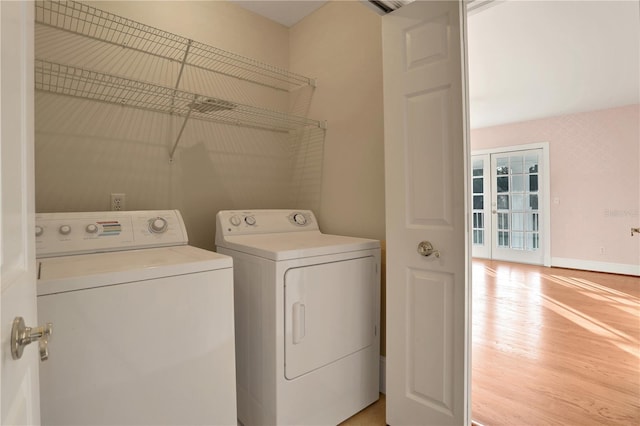 laundry room with separate washer and dryer and light hardwood / wood-style floors