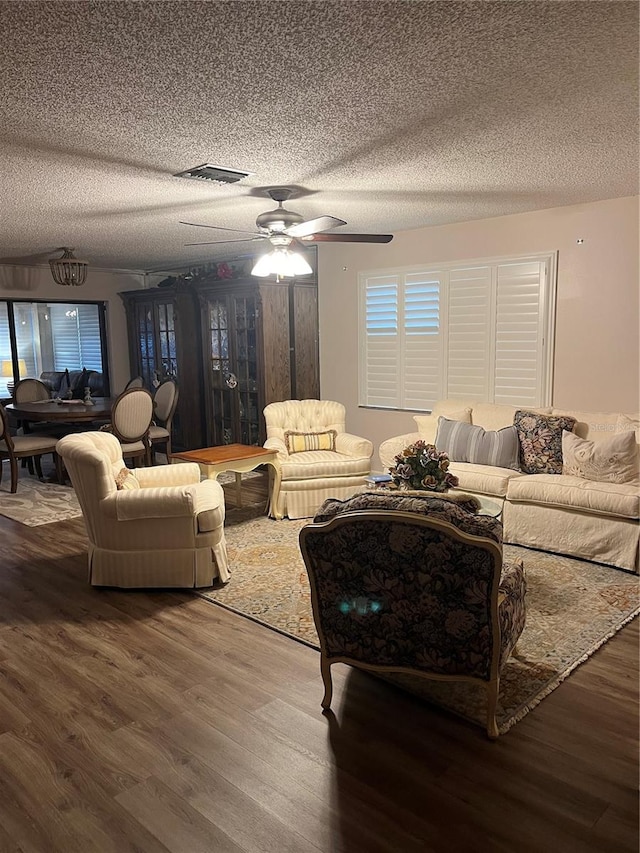 living room featuring hardwood / wood-style floors, ceiling fan, and a textured ceiling