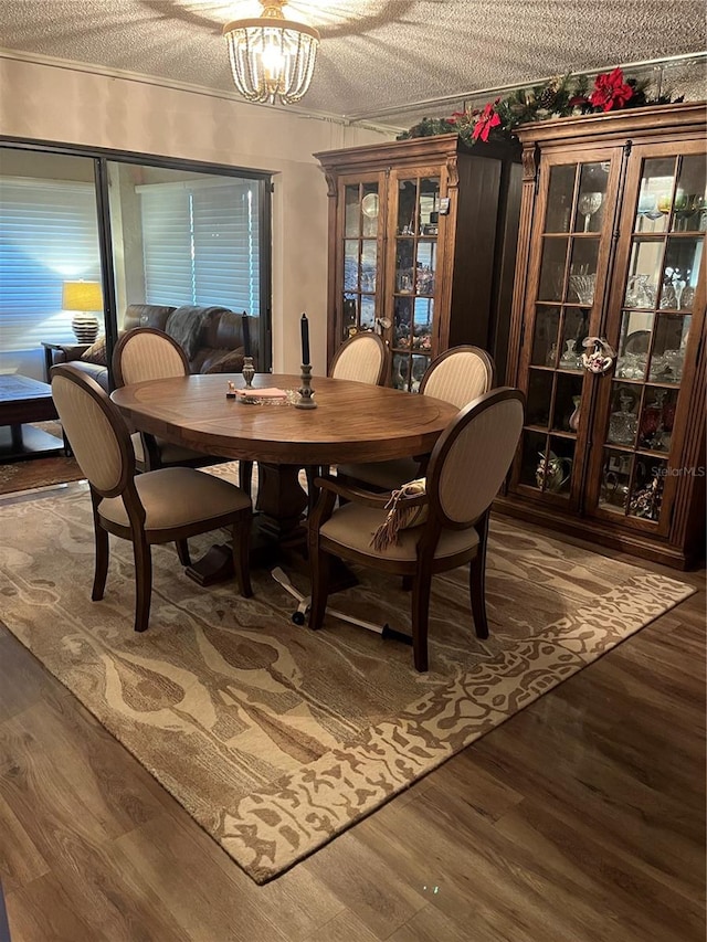 dining room with a notable chandelier, dark hardwood / wood-style floors, ornamental molding, and a textured ceiling