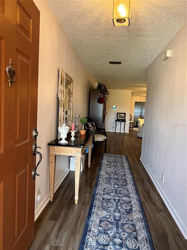 hall with a textured ceiling and dark hardwood / wood-style floors