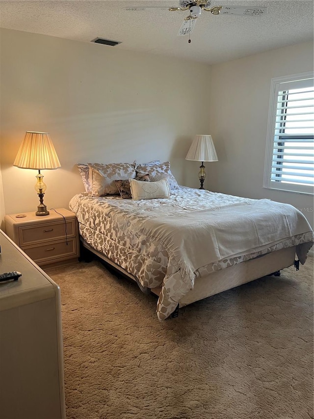 carpeted bedroom with a textured ceiling and ceiling fan