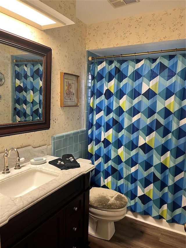 bathroom with hardwood / wood-style flooring, vanity, toilet, and walk in shower