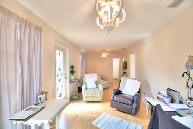 living room featuring ceiling fan with notable chandelier and wood-type flooring