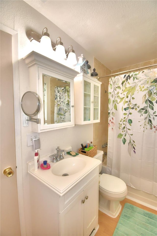 bathroom with a textured ceiling, hardwood / wood-style flooring, toilet, and vanity with extensive cabinet space