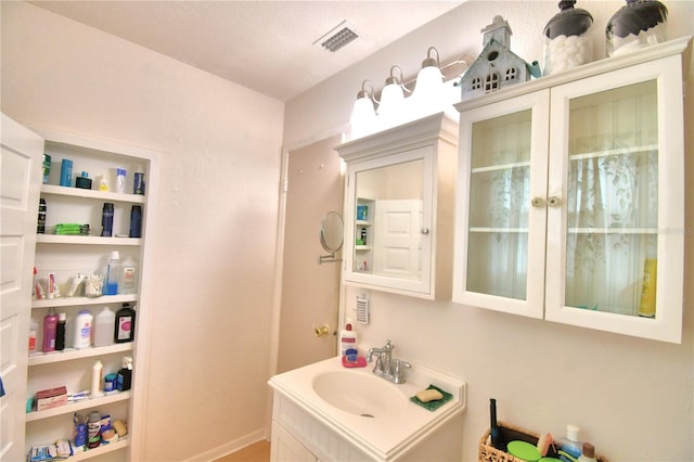 bathroom featuring vanity with extensive cabinet space and a textured ceiling