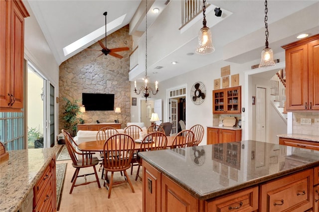 8608 Poinsettia Dr, Temple Terrace, FL 33637 - kitchen featuring lofted ceiling with skylight, a center island, a stone fireplace, light wood-type flooring, and dark stone counters