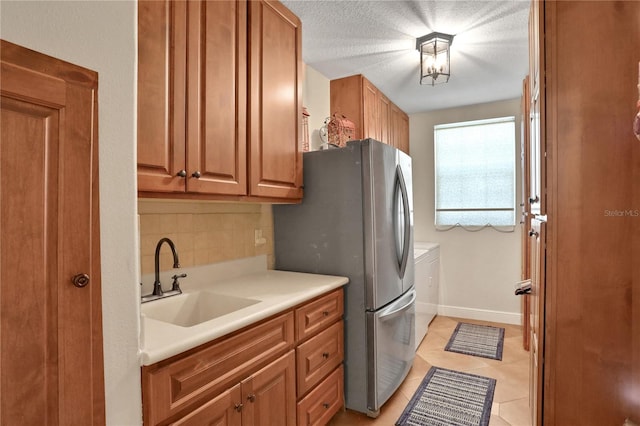 8608 Poinsettia Dr, Temple Terrace, FL 33637 - kitchen featuring light tile floors, a textured ceiling, sink, tasteful backsplash, and stainless steel fridge