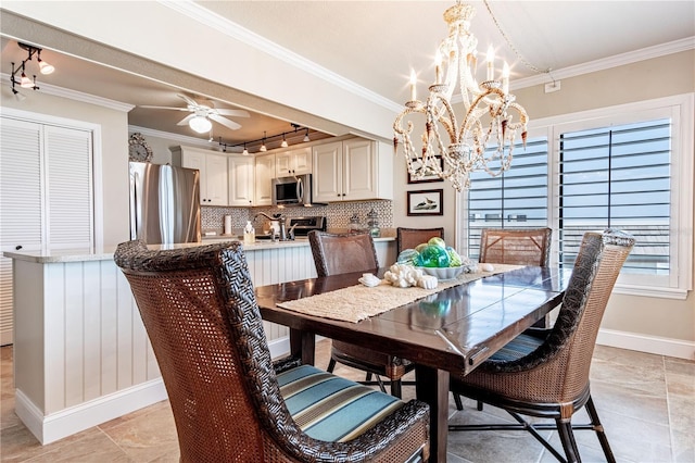 tiled dining area with sink, track lighting, ceiling fan with notable chandelier, and ornamental molding