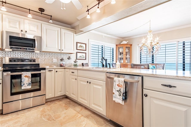 kitchen with appliances with stainless steel finishes, track lighting, tasteful backsplash, and a healthy amount of sunlight