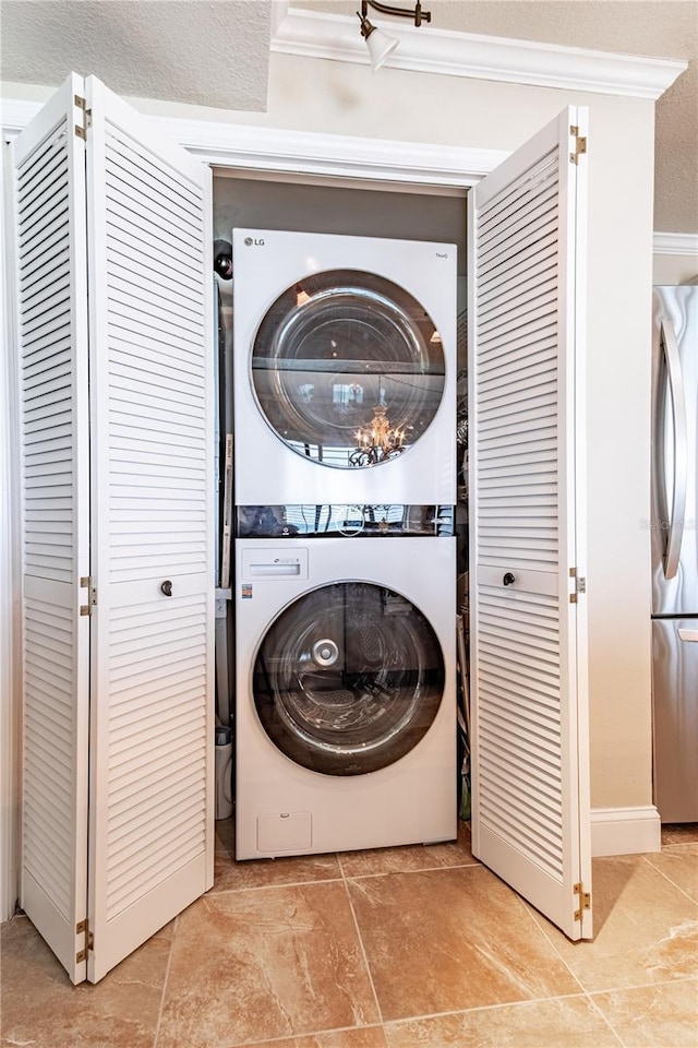 washroom featuring stacked washing maching and dryer and ornamental molding