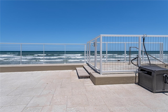 view of patio with a water view and a beach view