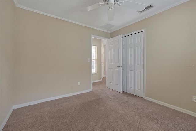 unfurnished bedroom with carpet flooring, a closet, ceiling fan, and crown molding