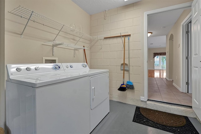 washroom with washer and clothes dryer, a textured ceiling, and hookup for a washing machine