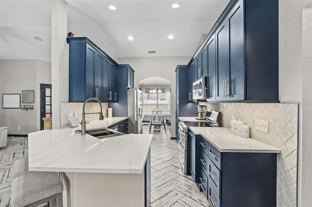 kitchen featuring stainless steel appliances, arched walkways, blue cabinets, and a peninsula